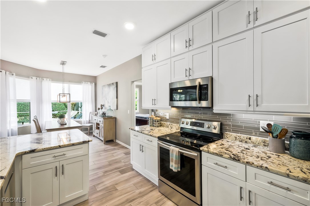 15047 Balmoral Loop Fort Myers, FL 33919 - Photo 11 of 37 a kitchen with stainless steel appliances granite countertop white cabinets granite counter tops and a hard wood floors