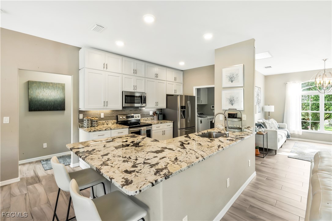 15047 Balmoral Loop Fort Myers, FL 33919 - Photo 8 of 37 a living room with stainless steel appliances kitchen island granite countertop a kitchen view and living room couch