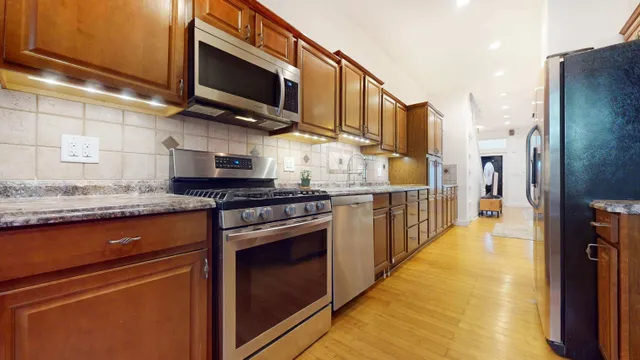 a kitchen with stainless steel appliances granite countertop a refrigerator a oven and a sink
