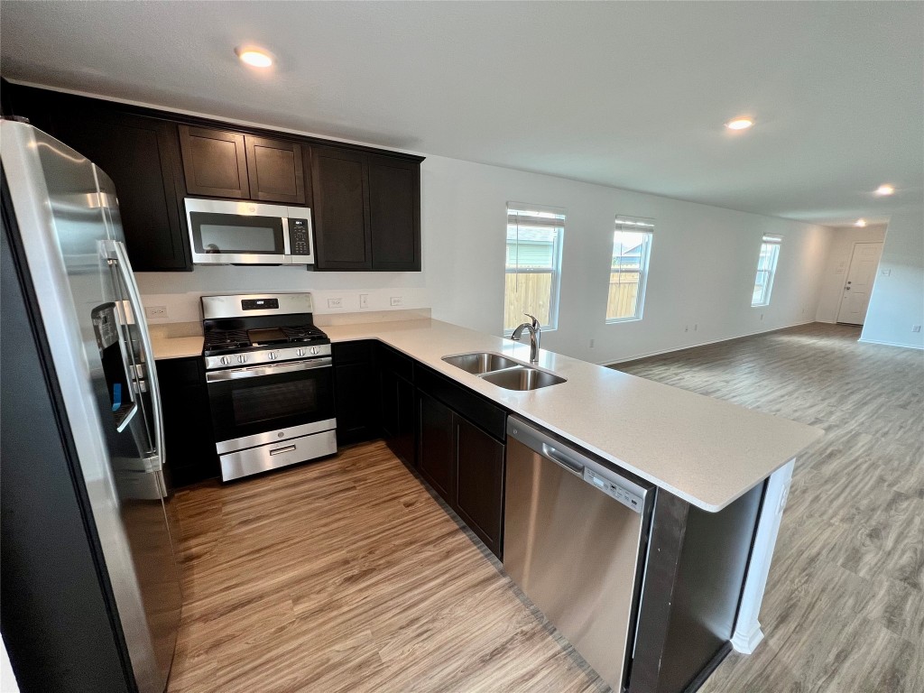 412 Halfmoon Drive Lockhart, TX 78644 - Photo 1 of 1 a kitchen with stainless steel appliances a sink a stove a microwave a sink a refrigerator white cabinets and wooden floor