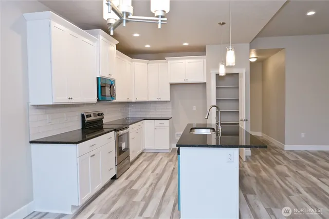 a kitchen with granite countertop a sink a counter space appliances and cabinets