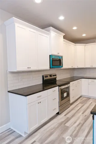 a kitchen with granite countertop white cabinets and stainless steel appliances