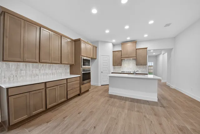 a view of a kitchen with kitchen island a sink stainless steel appliances and cabinets