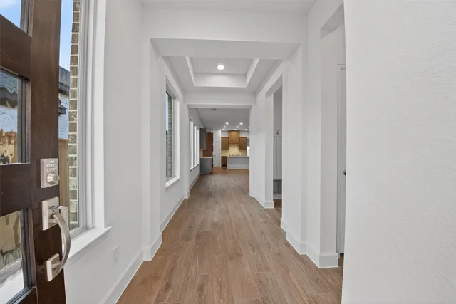 a view of a hallway with wooden floor and a living room