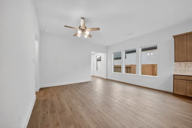 a view of empty room with wooden floor and ceiling fan