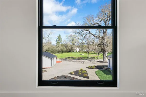 a view of an empty room with a window and kitchen view