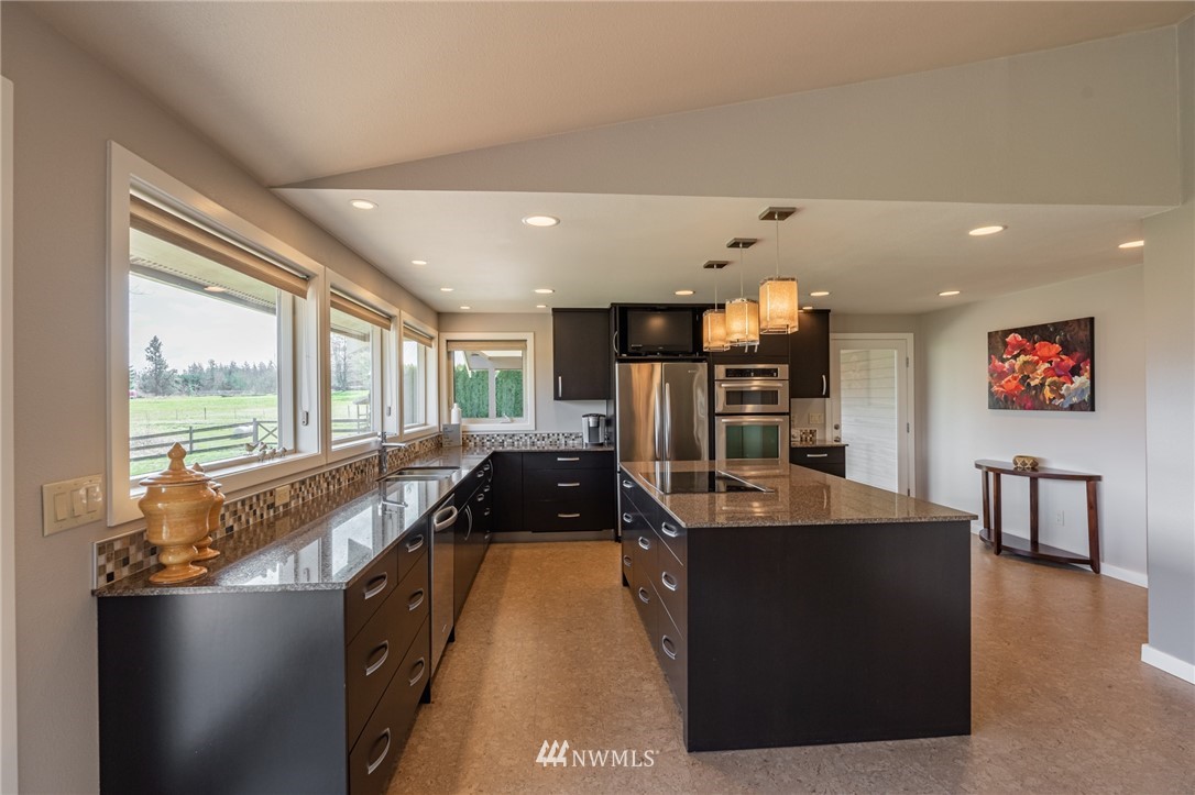 5434 Noon Road Bellingham, WA 98226 - Photo 34 of 40 a view of a kitchen with kitchen island a large counter top space a large window and stainless steel appliances