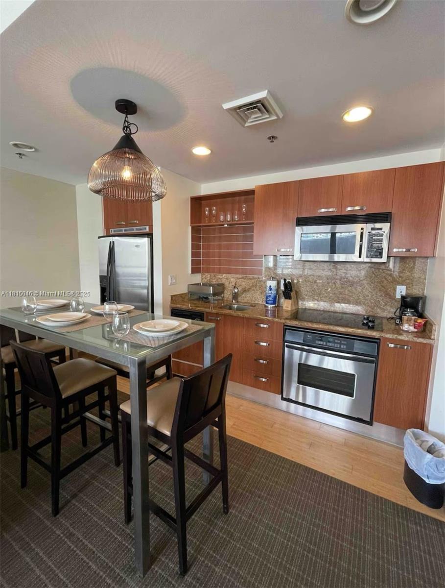 a kitchen with a stove a sink dishwasher a dining table and chairs with wooden floor