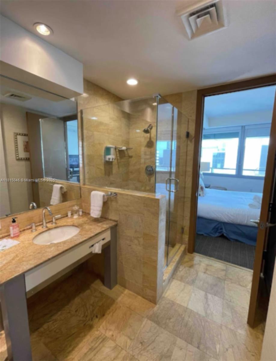 1395 Brickell Avenue, Unit 2814 Miami, FL 33131 - Photo 9 of 17 a bathroom with a tub a sink and a large mirror