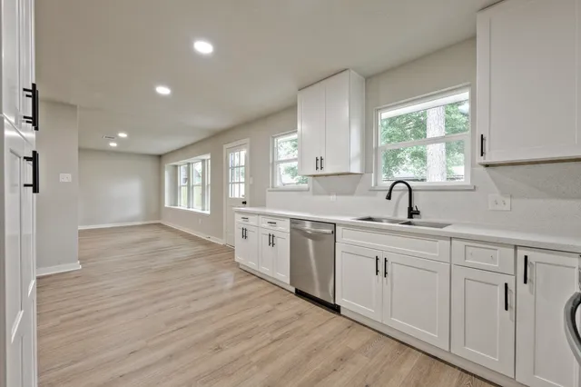 a kitchen with white cabinets and wooden floors