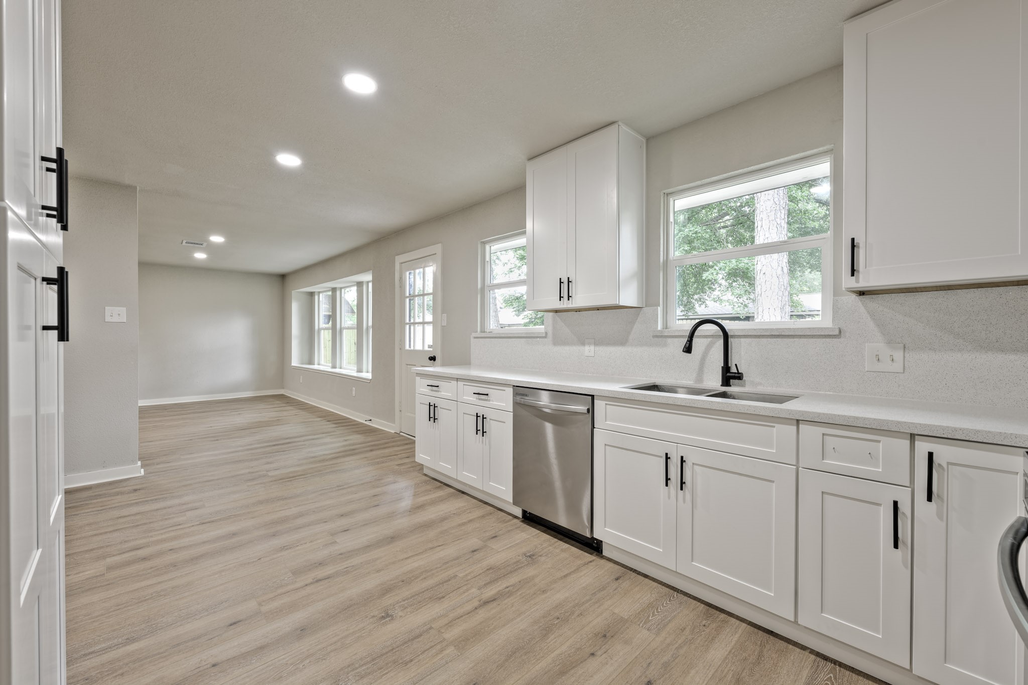 a kitchen with white cabinets and wooden floors