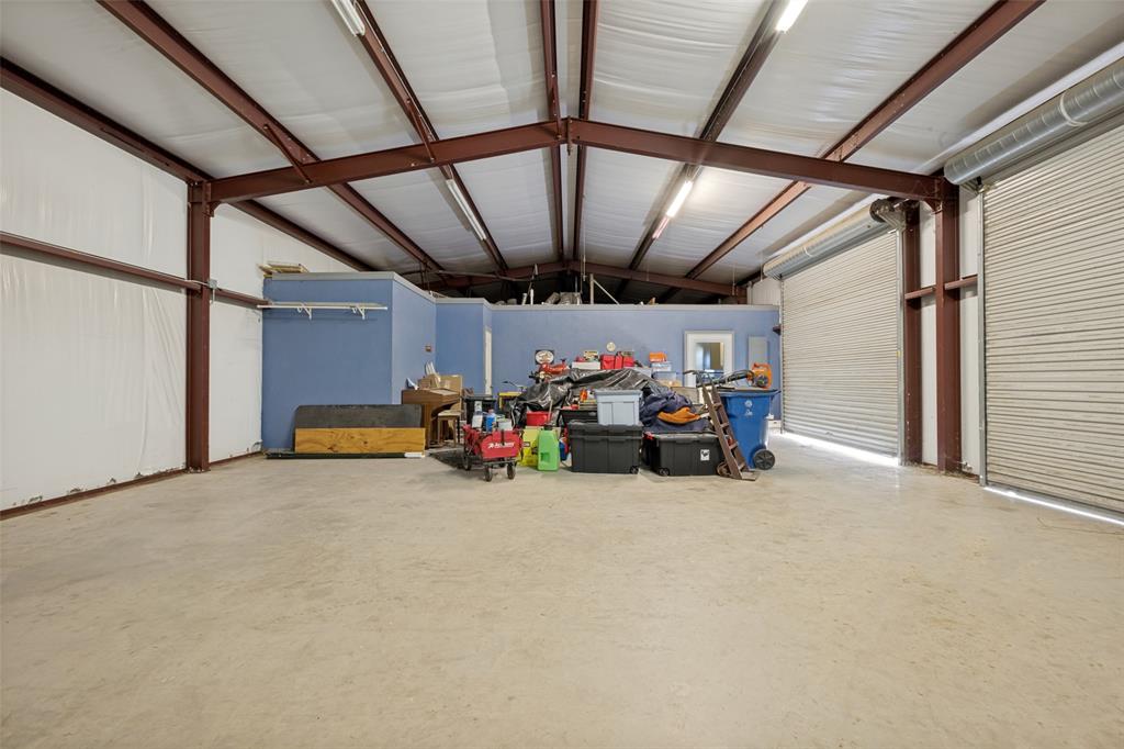 8400 Holder Road Northlake, TX 76247 - Photo 28 of 36 Barndo garage space interior with exposed steel beam construction, a concrete floor, and two large roll-up doors
