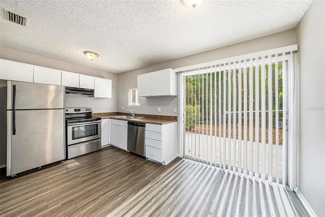 a kitchen with granite countertop stainless steel appliances a refrigerator and cabinets