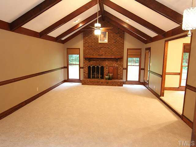 2215 Yorkgate Drive Raleigh, NC 27612 - Photo 4 of 24 Step into the foyer and look ahead to this huge, but cozy family room with vaulted ceiling with beams, new fan and light fixture and a masonry fireplace with gas logs. Den/Family/Great Room