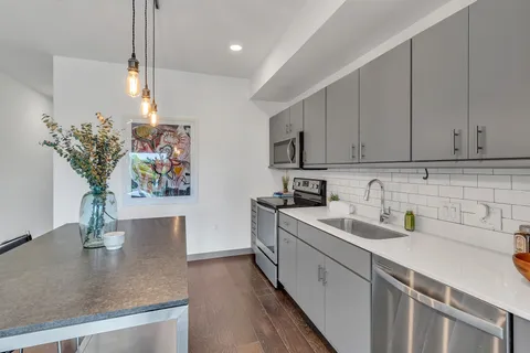 a kitchen with stainless steel appliances granite countertop a sink a stove and white cabinets