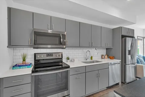 a kitchen with stainless steel appliances granite countertop white cabinets sink and a granite counter top