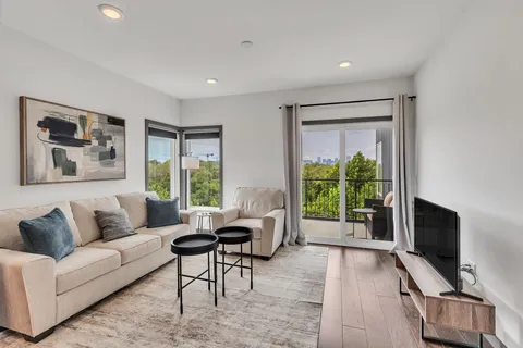 a living room with furniture a flat screen tv and a window