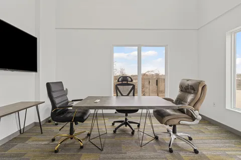 a view of a workspace with furniture and a window