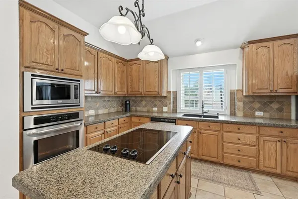 a kitchen with granite countertop a sink stainless steel appliances and cabinets