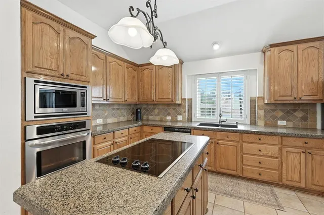 a kitchen with granite countertop a sink stainless steel appliances and cabinets