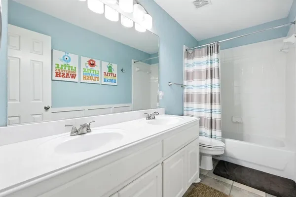 a bathroom with a double vanity sink toilet mirror and bathtub