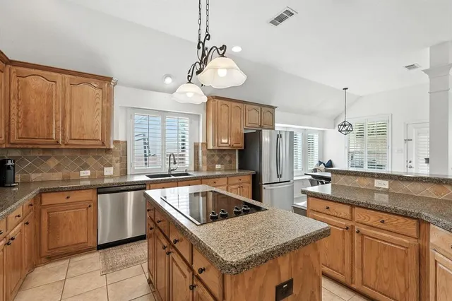 a kitchen with a sink a center island a counter space and stainless steel appliances