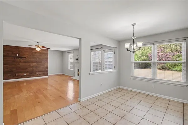 an empty room with windows fireplace and a kitchen view