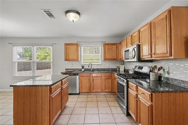 a kitchen with stainless steel appliances granite countertop a refrigerator and a stove top oven