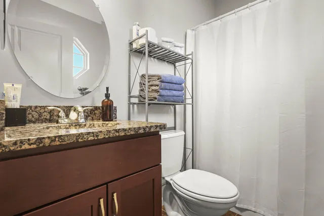 a bathroom with a granite countertop sink mirror vanity and toilet
