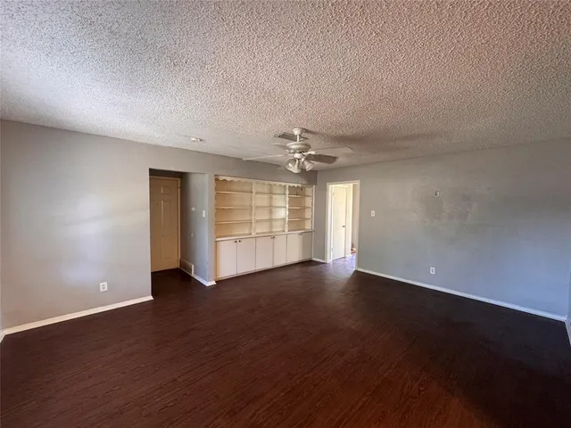an empty room with wooden floor chandelier and windows