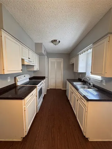 a kitchen with granite countertop a sink a counter top space and cabinets