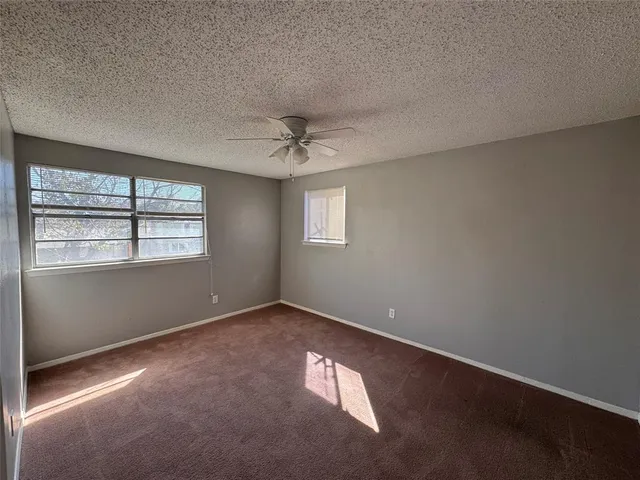 an empty room with windows and chandelier fan