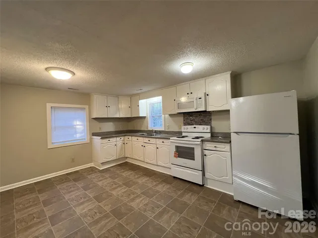 a kitchen with white cabinets and white appliances