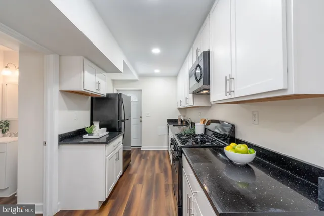 a kitchen with stainless steel appliances a counter top space cabinets and wooden floor