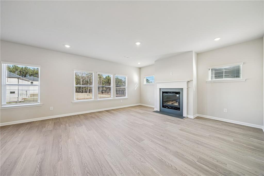 1428 High Fls Lane Grayson, GA 30017 - Photo 5 of 39 an empty room with windows a fireplace and wooden floor