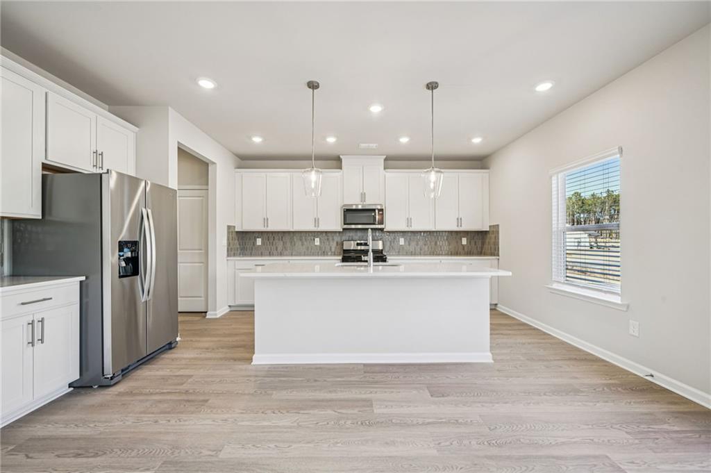 1428 High Fls Lane Grayson, GA 30017 - Photo 9 of 39 a view of kitchen with granite countertop a refrigerator oven a sink dishwasher and white cabinets with wooden floor
