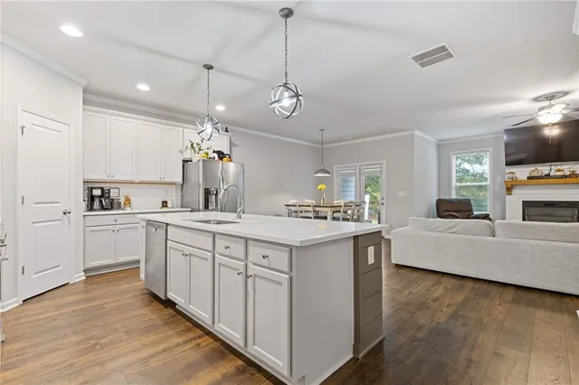 a kitchen with kitchen island granite countertop a sink cabinets and wooden floor