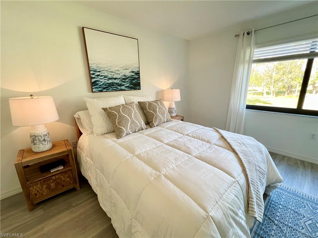 75 St Andrews Boulevard, Unit B203 Naples, FL 34113 - Photo 15 of 38 a bedroom with a bed and wooden floor
