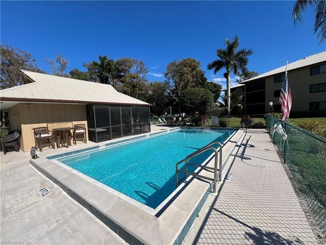 a view of swimming pool with lounge chair and dinning table under an umbrella