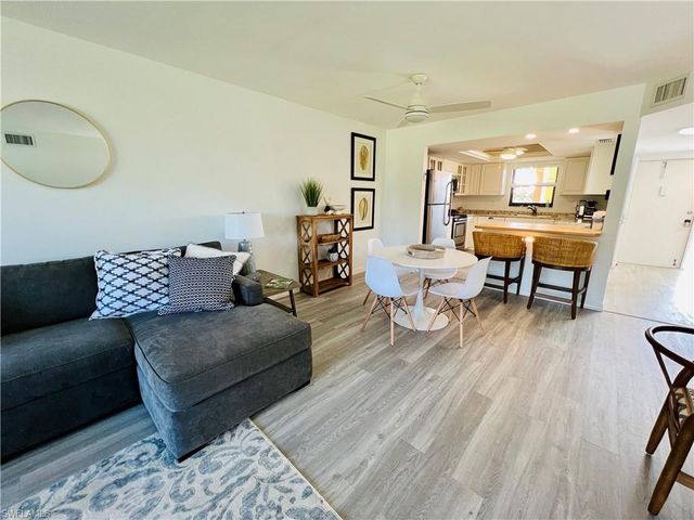 a living room with couches and a dining table with wooden floor