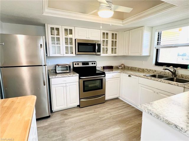 a kitchen with stainless steel appliances granite countertop a refrigerator stove a sink and microwave with wooden floor