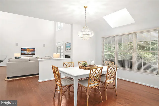 a dining room with wooden floor a chandelier a wooden table and chairs