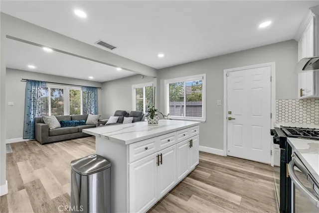 a view of a kitchen counter top space a sink wooden floor and windows