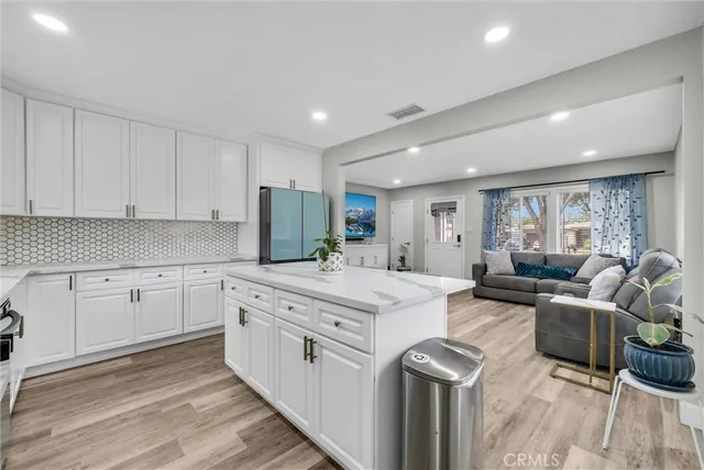 a large white kitchen with cabinets appliances and a wooden floor