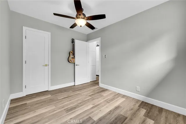 an empty room with wooden floor ceiling fan and windows