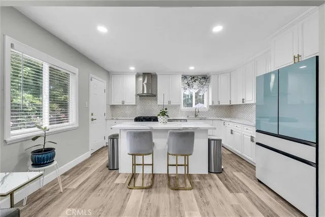 a kitchen with stainless steel appliances a table chairs refrigerator microwave and cabinets