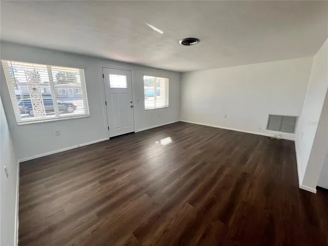 an empty room with wooden floor and windows