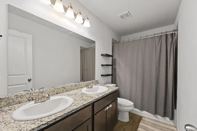 a bathroom with a granite countertop sink a toilet and a mirror