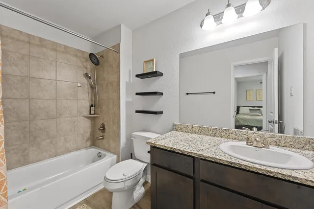 a bathroom with a granite countertop sink a toilet and shower