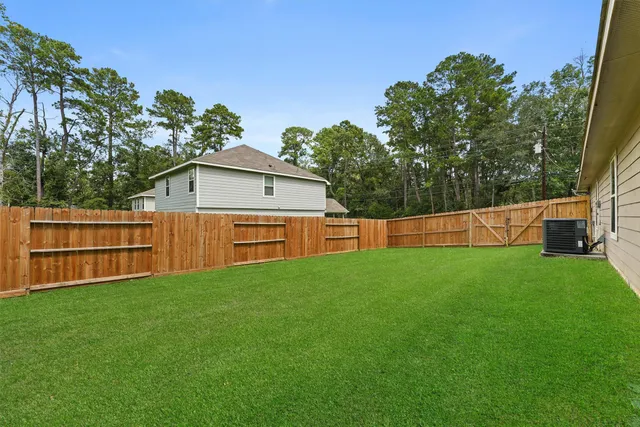 a backyard of a house with wooden fence and large trees